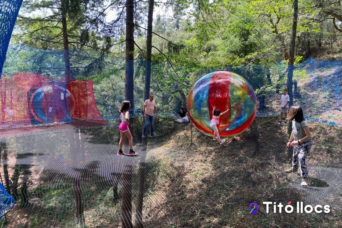 Vista del parc d'aventura amb els visitants i els globus zorb entre els arbres