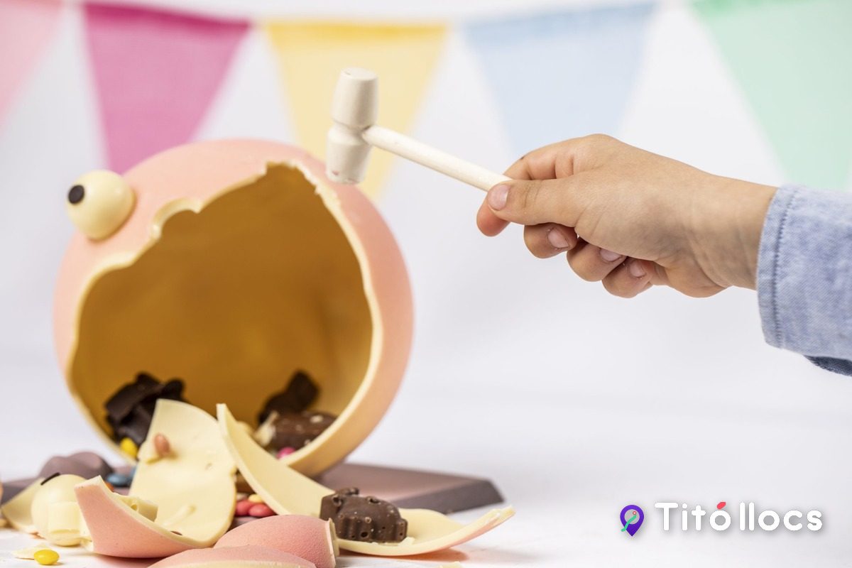 Una mà colpejant una mona de xocolata amb un martell de carmanyola per trobar les sorpreses