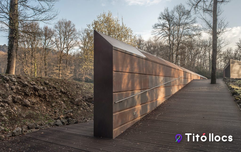 Mur d'acer corten i passarel·la de fusta del camí d'accés que baixa cap a la pista, a l'Estadi Tossols-Basil d'Olot