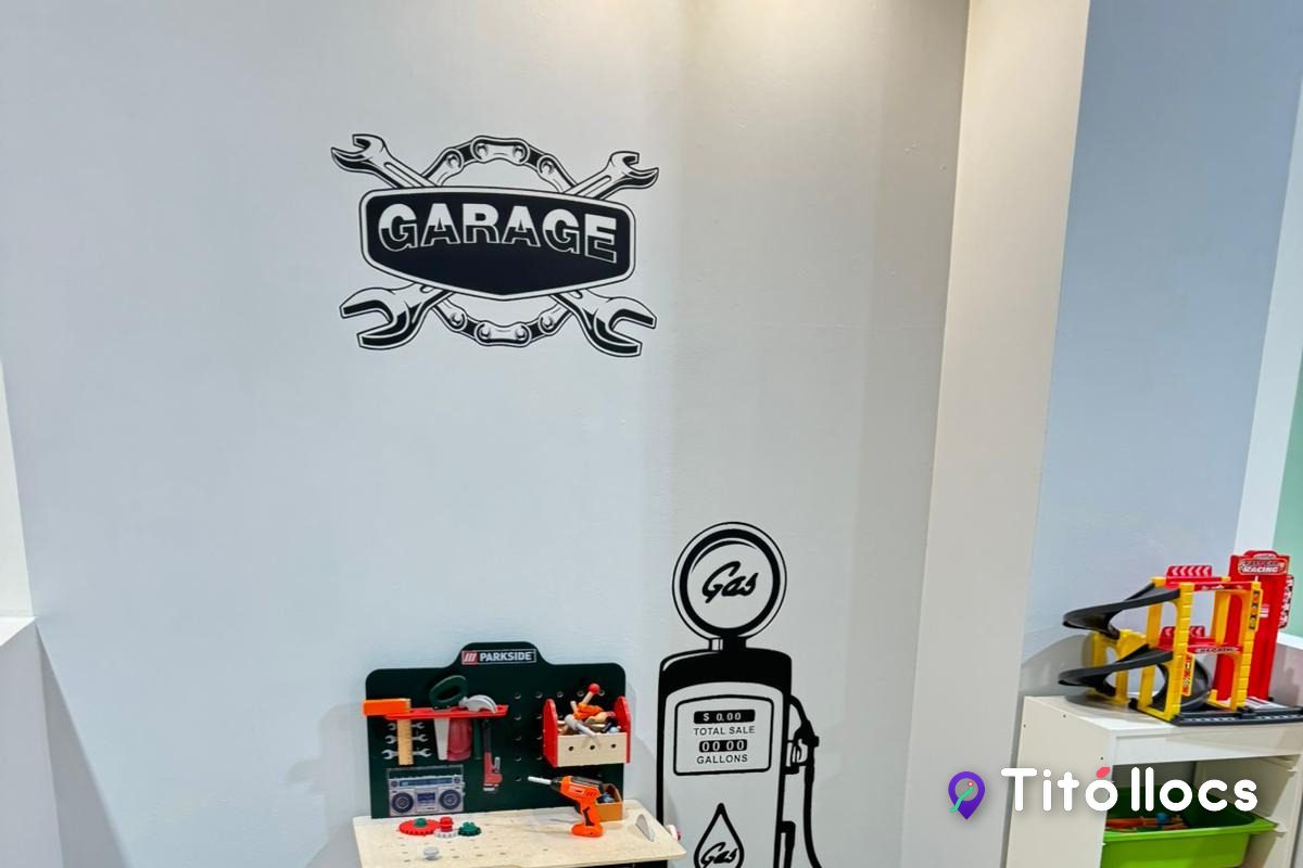 Racó del garatge de L'Esbarjo, amb el rètol GARAGE, cotxes de joguina i una benzinera de fusta