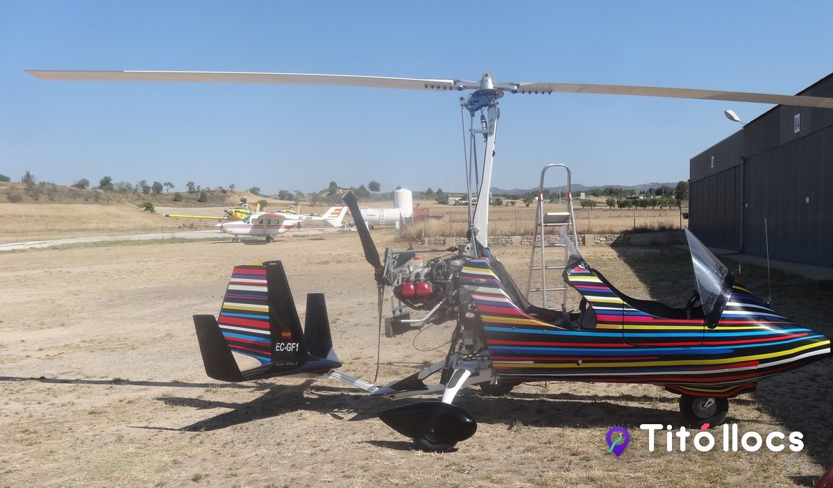 Girocòpter acolorit davant d'un hangar de l'aeròdrom d'Igualada-Òdena