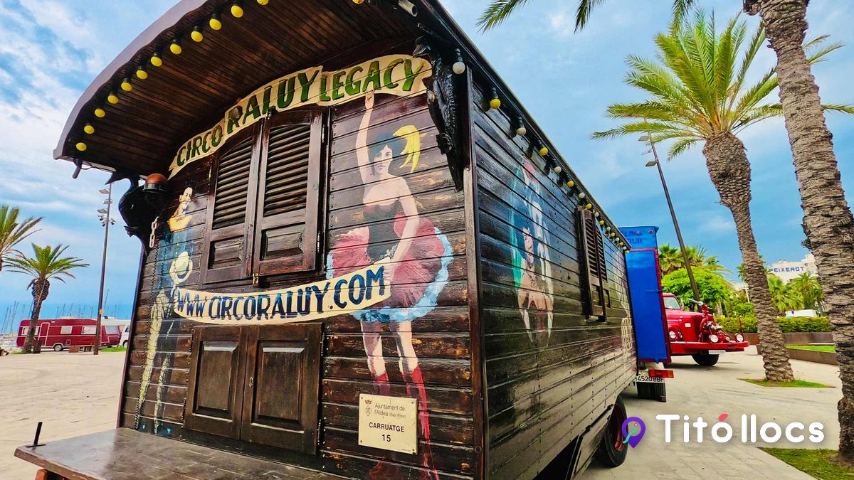 Caravana de fusta pintada amb el nom Circo Raluy Legacy i una ballarina, amb palmeres i mar de fons