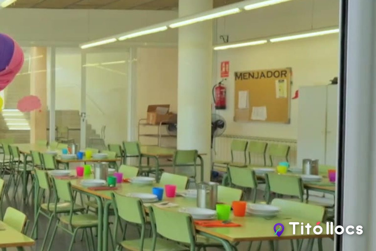 El menjador de l'escola amb el rètol de la paret, les taules parades i les cadires de colors