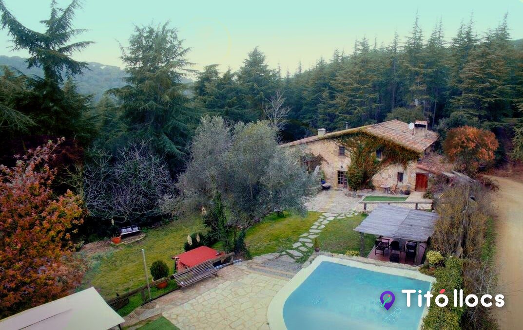 Vista aèria de la masia, la piscina i el bosc del voltant, a Masia Cal Coix