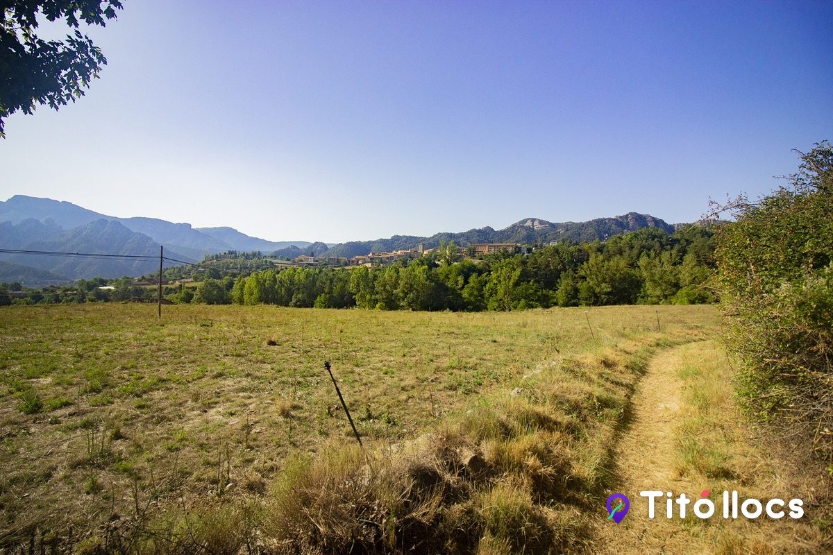 Camí de terra entre camps de la Vall de Lord, amb la vila de Sant Llorenç de Morunys al fons