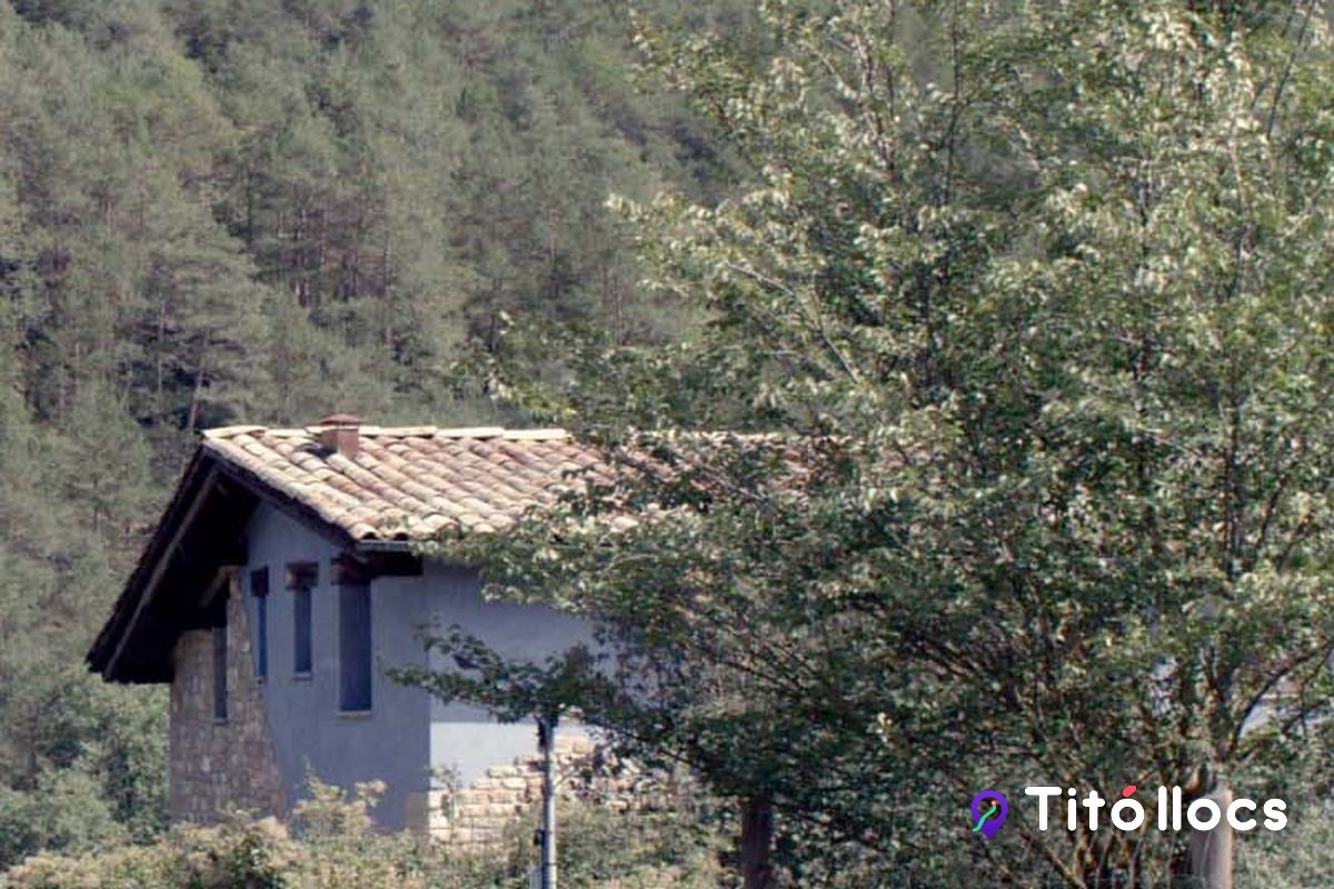 Casa de pedra amb teulada de teules entre boscos, a la Vall de Lord