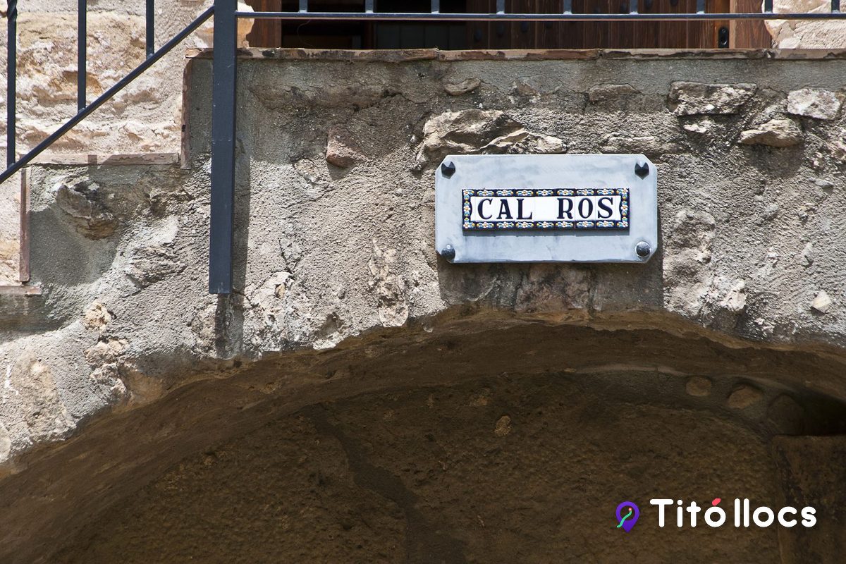 Placa de ceràmica amb el nom «Cal Ros» a la paret de pedra de la masia, a Cistella