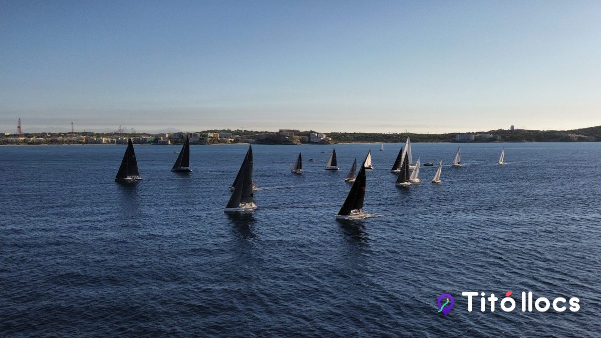 Velers enfilats en regata sobre la badia, amb la costa de Salou al fons